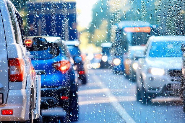 gotas en vidrio auto carretera lluvia noche de otoño / fondo abstracto de otoño en la ciudad, tráfico de automóviles, viaje romántico en coche