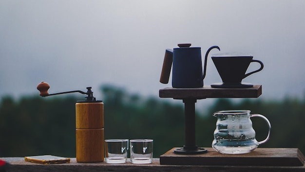 Gotejamento de café na mesa de madeira com paisagem montanhosa em tom escuro