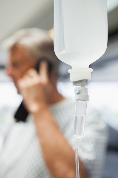 Gotejamento intravenoso com paciente no telefone em segundo plano
