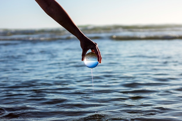 Foto goteo de agua de mar de una esfera de cristal