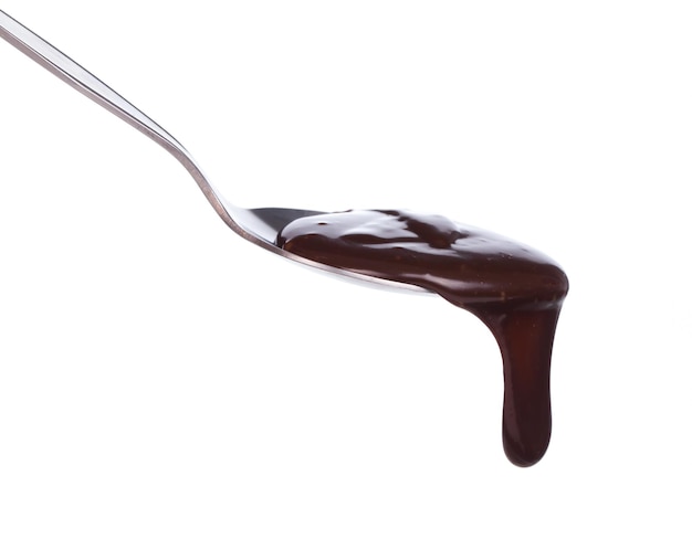 Foto goteo de chocolate de una cuchara aislado sobre fondo blanco.