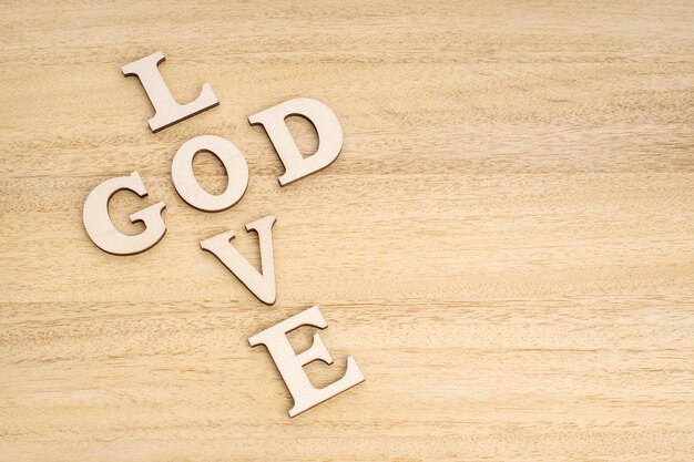 Gott ist das Konzept der Liebe Wörter, die ein Kreuz auf einem Holztisch bilden