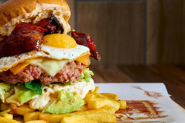 Gourmet-Hamburger mit Fleisch, karamellisierten Zwiebeln, Tomaten, Speck und Spiegelei