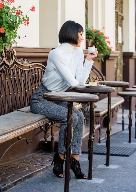 Gourmet-Konzept Frau attraktive elegante Brünette genießen Gourmet-Kaffee Café Terrasse Hintergrund Angenehme Zeit und Entspannung Köstliche und Gourmet-Getränk Mädchen entspannen Café mit Kaffee und Dessert