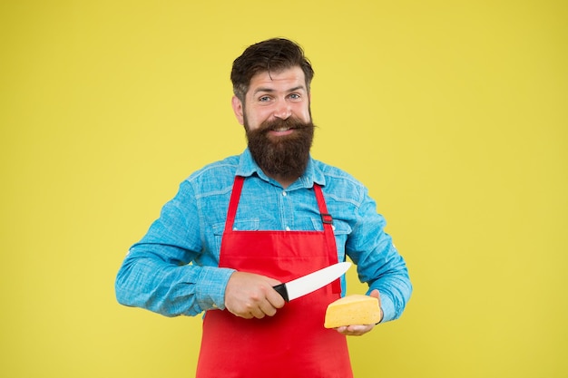 Gourmet-Produkt Milchprodukt aus Milch Online-Shopping Diät und Ernährung Verkäuferkonzept Käsehersteller Bärtiger Mann in Schürze hält ein Stück Käse in der Hand Ladenpersonal Beruf Käse kaufen