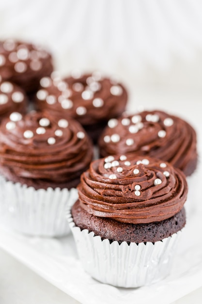 Gourmet-Schokoladen-Cupcakes verziert mit silbernen Kugeln auf Schokoladenglasur.