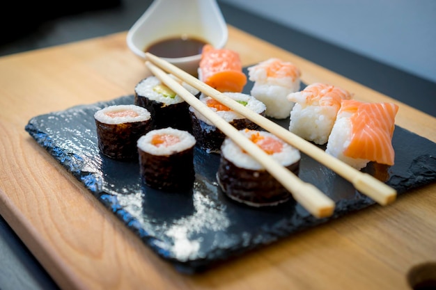 Gourmet, Sushi sobre una mesa de madera sobre placa de pizarra negra con salsa de soja y palillos