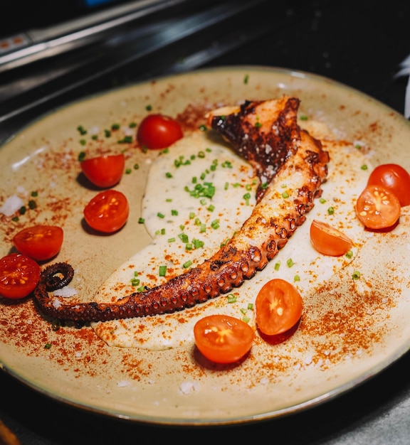 Foto gourmetgericht mit gegrilltem tintenfischtentakel in einem schicken restaurant.