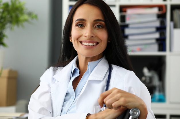 GP hembra madura sentada en la mesa de trabajo mirando