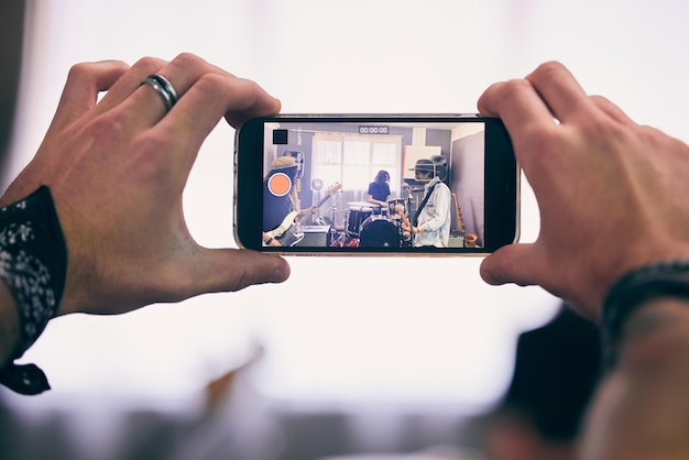 Grabación de teléfonos inteligentes y banda de garaje tocando música en vivo para transmisión de conciertos en Internet o publicación en redes sociales Personas móviles e instrumentos juntos para eventos creativos o audiciones de festivales en línea