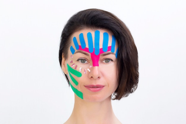 Grabado facial, primer plano de la cara de una niña con cinta cosmetológica antiarrugas. Grabado estético facial.