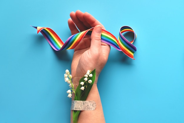 Gracias doctores y enfermeras! Cinta del arco iris en mano de mujer madura con flores de manzanilla y ramo de hierba adjunta con parche de asistencia médica