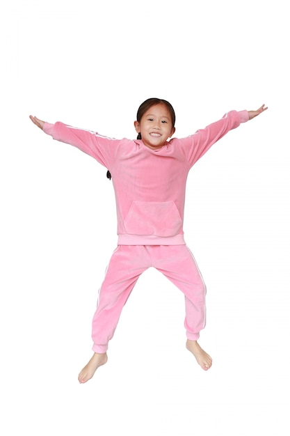 Graciosa niña asiática niño en tela deportiva rosa saltando en el aire