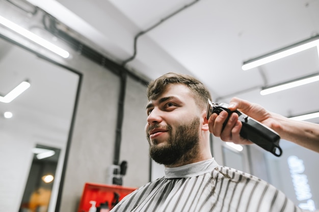 Gracioso cliente adulto corta barba y cabeza en peluquería
