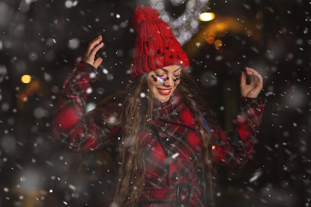 Gracioso joven mujer de pelo largo disfrutando de la nieve en la feria de Navidad