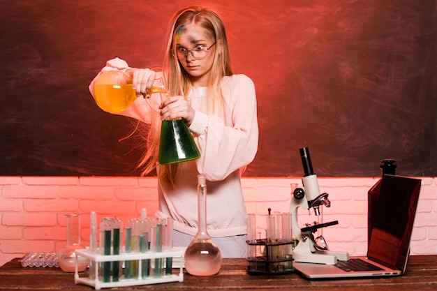 Gracioso niño de escuela química haciendo experimentos en la explosión de laboratorio en el laboratorio de ciencia y educación