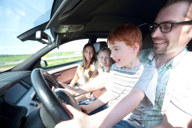 Gracioso padre y su pequeño hijo conduciendo un coche el concepto de paternidad