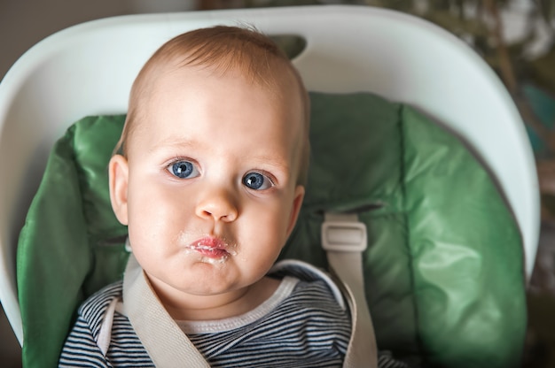 Gracioso retrato de niño comiendo closeup alimentación complementaria del niño con papilla a los 9 meses Calabacín, coliflor, brócoli