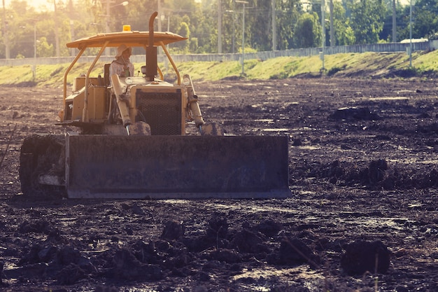 Grader nivelar el vertedero en el sitio de construcción