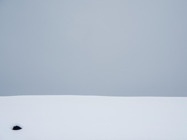 Foto gradiente cinza, monte de neve em um fundo de céu cinza. superfície nevada, abstrato.