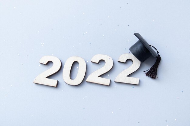 Foto graduação 2022 usando chapéu de pós-graduação no número de madeira 2022 em fundo cinza com glitter