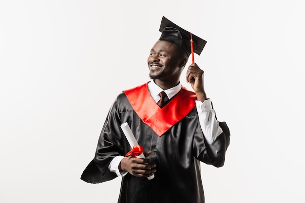 Graduação Homem africano feliz sorrindo e segurando diploma com honras em suas mãos sobre fundo branco Homem africano graduado se formou na universidade e obteve mestrado