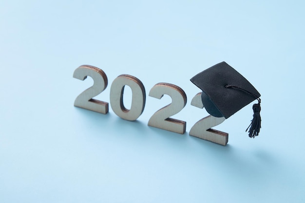Graduación 2022 con sombrero de graduado en madera número 2022 sobre fondo azul. enfoque variable