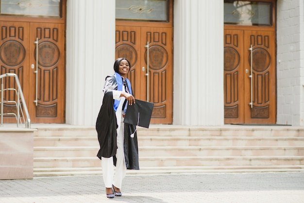 Graduada bastante afroamericana fuera del edificio de la universidad