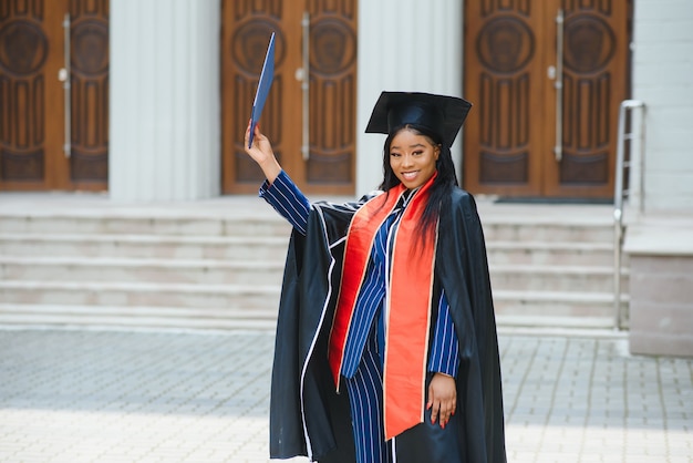 Graduada bastante afroamericana fuera del edificio de la universidad