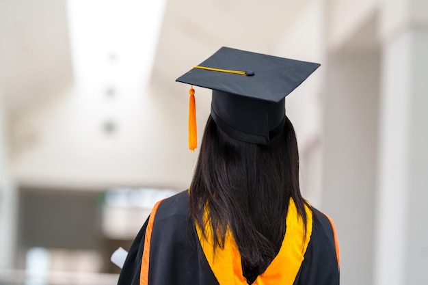 Graduadas femininas usam vestidos pretos e borlas amarelas esperando para participar da cerimônia de formatura na universidade