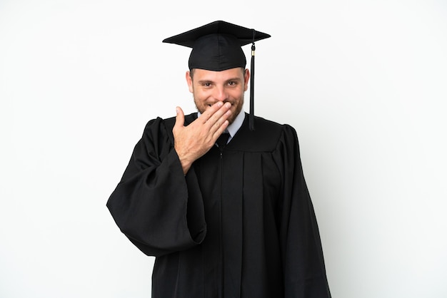 Graduado brasileño universitario joven aislado sobre fondo blanco feliz y sonriente cubriendo la boca con la mano