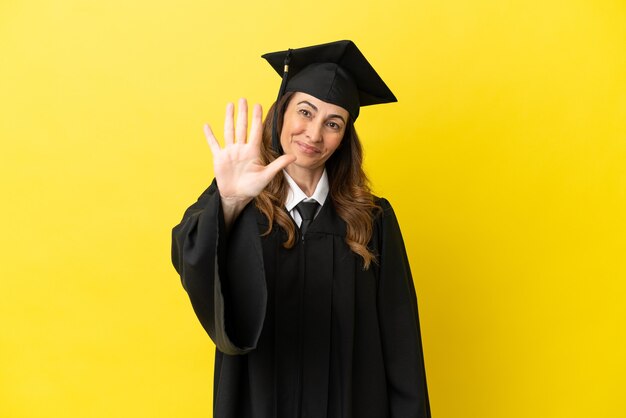 Graduado de meia-idade isolado em fundo amarelo, contando cinco com os dedos