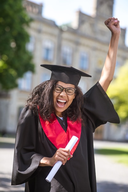 Graduado. Una estudiante que se siente increíble por la graduación universitaria