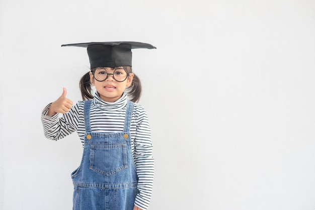 Graduado de niño de escuela asiática feliz con gorro de graduación