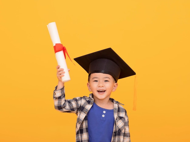 Graduado de niño de escuela asiática feliz en gorro de graduación