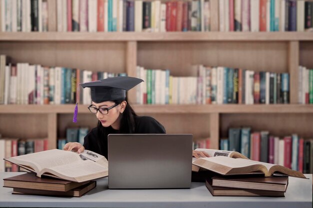 Graduado ocupado leyendo libros en la biblioteca