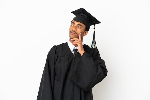 Graduado universitario afroamericano sobre fondo blanco aislado pensando en una idea mientras mira hacia arriba