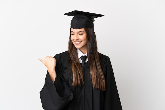 Graduado universitario brasileño adolescente sobre fondo blanco aislado apuntando hacia el lado para presentar un producto