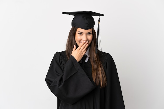 Graduado universitario brasileño adolescente sobre fondo blanco aislado feliz y sonriente cubriendo la boca con la mano