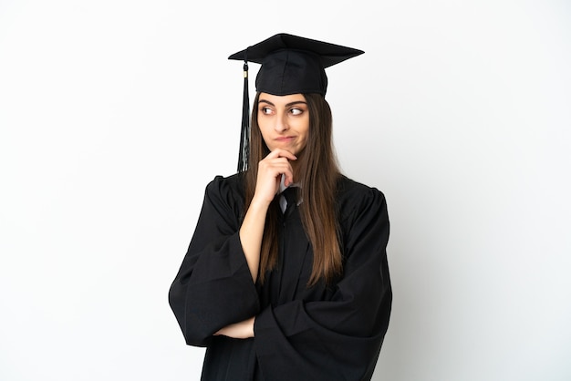 Graduado universitario joven aislado sobre fondo blanco con dudas y pensamiento