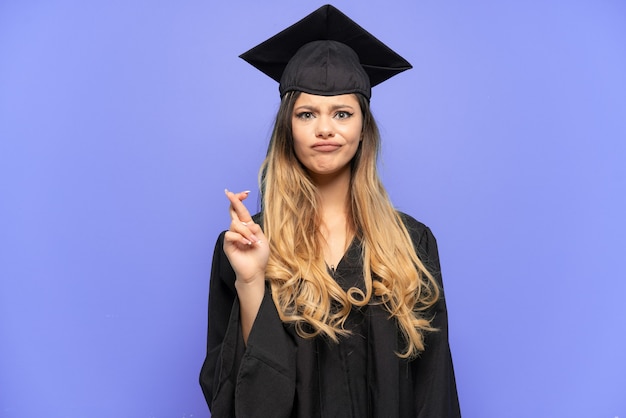 Graduado universitario joven chica rusa aislada sobre fondo blanco con los dedos cruzando y deseando lo mejor