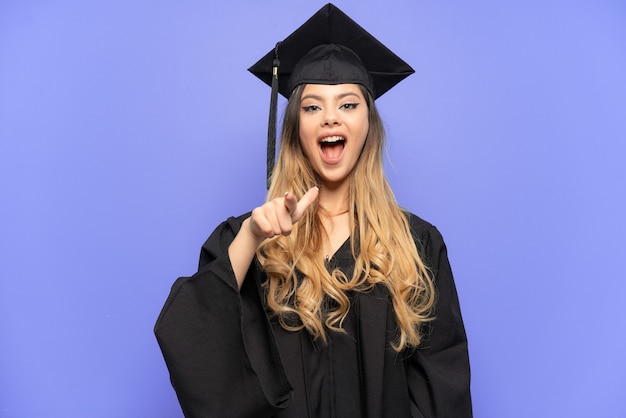 Graduado universitario joven chica rusa aislada sobre fondo blanco sorprendido y apuntando hacia el frente