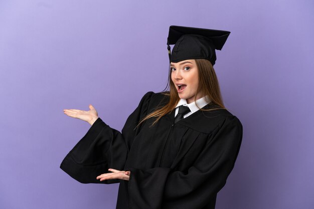 Graduado universitario joven sobre fondo púrpura aislado con expresión de sorpresa mientras mira de lado