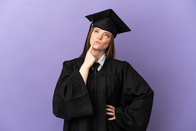 Graduado universitario joven sobre fondo púrpura aislado que tiene dudas mientras mira hacia arriba