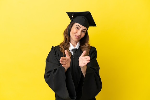 Graduado universitario de mediana edad aislado sobre fondo amarillo aplaudiendo después de la presentación en una conferencia