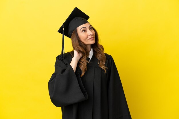 Graduado universitario de mediana edad aislado sobre fondo amarillo pensando en una idea