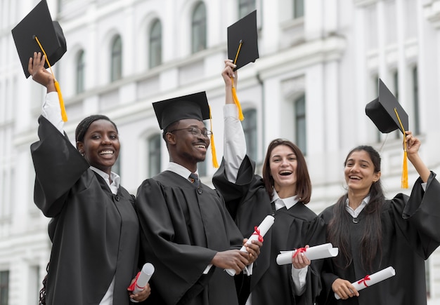 Foto graduados felizes jogando bonés para cima