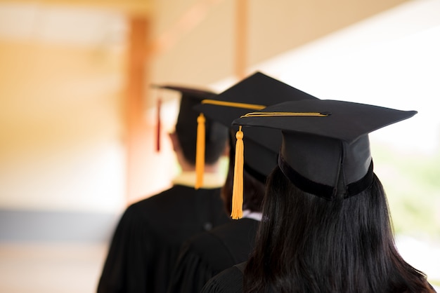 Graduados negros usam ternos pretos no dia da formatura na universidade.