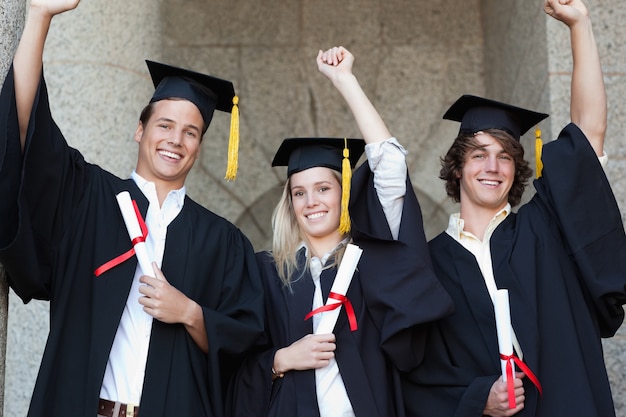 Graduados sosteniendo su diploma mientras levanta el brazo