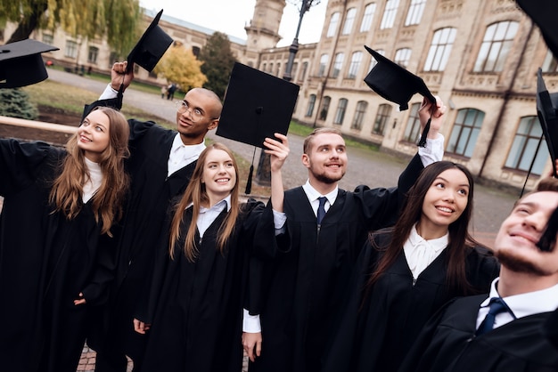 Los graduados de la universidad levantan sus gorras.